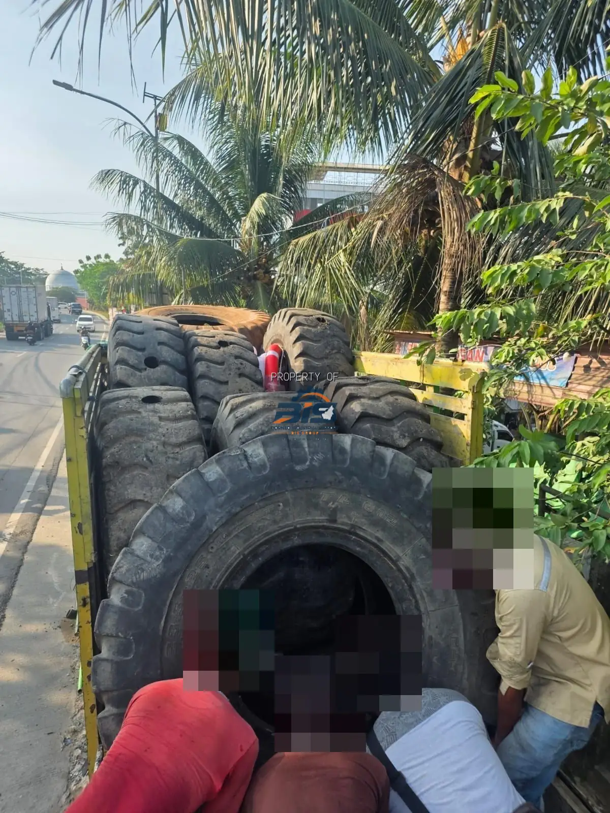 Pekerja memuat ban dapra loader ke truk, wajah disamarkan