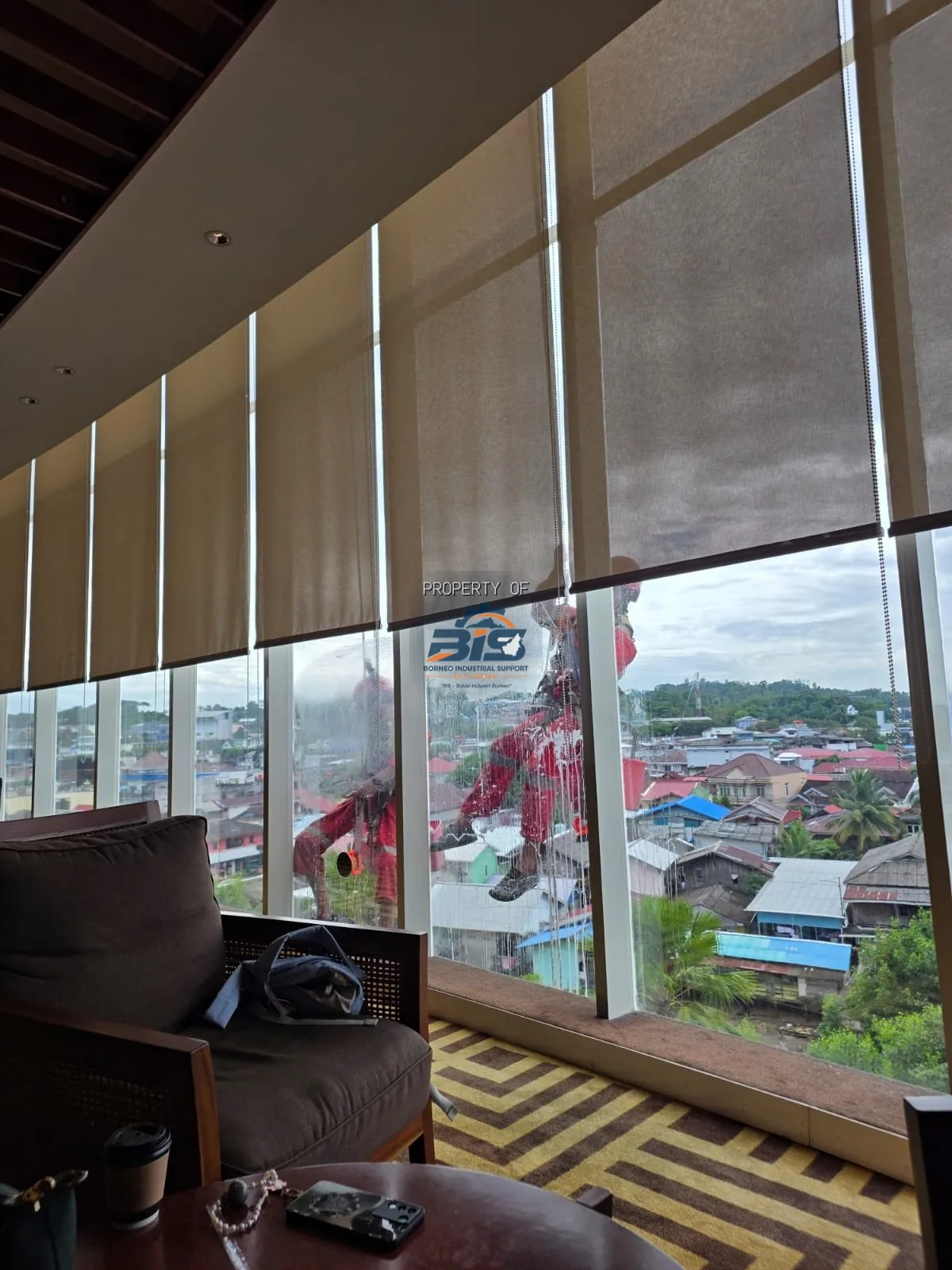 Teknisi rope access bekerja di fasad kaca gedung tinggi