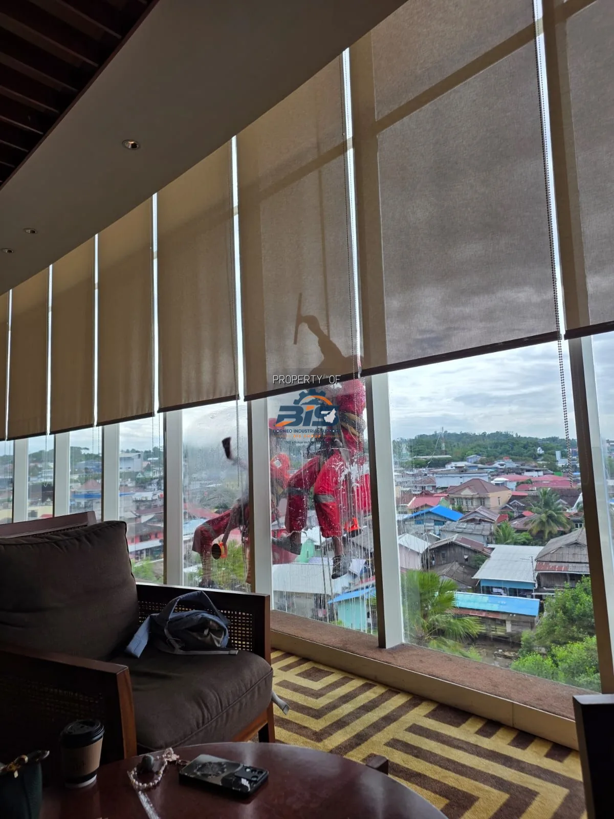 Teknisi rope access membersihkan fasad kaca gedung tinggi